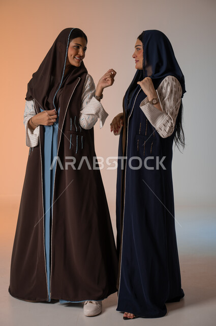  ايماءات الثقة والوقوف أمام الكاميرا، ارتداء العباءة الخليجية والنظارات الشمسية، الاحتراف في عرض آخر صيحات الموضة والجمال، بورتريه لعارضتان عربيتان سعوديتان خليجيتان، صورة الجسم بالطول الكامل، منتجات نسائيه سعوديه، شراء الأزياء والاكسسوارات, خلفية ملونة 