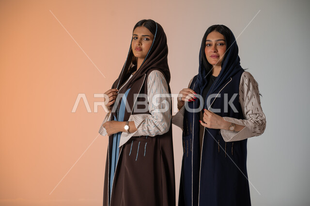 منتجات نسائيه سعوديه، ايماءات الثقة والوقوف أمام الكاميرا، ارتداء العباءة الخليجية والنظارات الشمسية، الاحتراف في عرض آخر صيحات الموضة والجمال، بورتريه لعارضتان عربيتان سعوديتان خليجيتان، شراء الأزياء والاكسسوارات, خلفية ملونة 