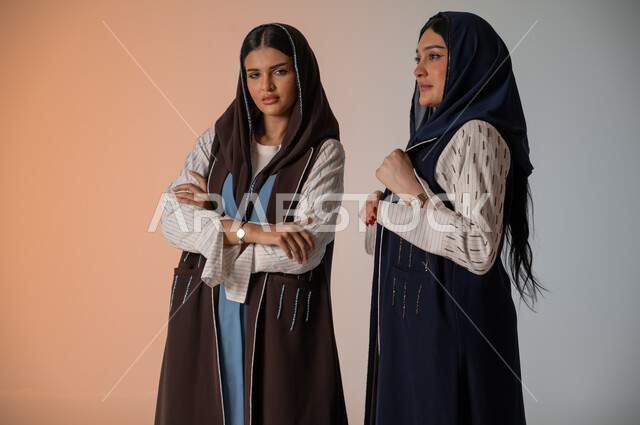 منتجات نسائيه سعوديه، ايماءات الثقة والوقوف أمام الكاميرا، ارتداء العباءة الخليجية والنظارات الشمسية، الاحتراف في عرض آخر صيحات الموضة والجمال، بورتريه لعارضتان عربيتان سعوديتان خليجيتان، شراء الأزياء والاكسسوارات, خلفية ملونة 
