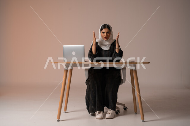 ايماءات الصراخ الشديد وعدم الرضا, الشعور بالإنزعاج و الرغبه بالإنتقام, بورتريه لامراة عربية خليجية سعودية محجبة ترتدي العباءة السوداء تجلس على الكرسي وتنظر إلى الكاميرا بتعابير الغضب،  استخدام التقنيات الحديثة المتطورة، خلفية بيج