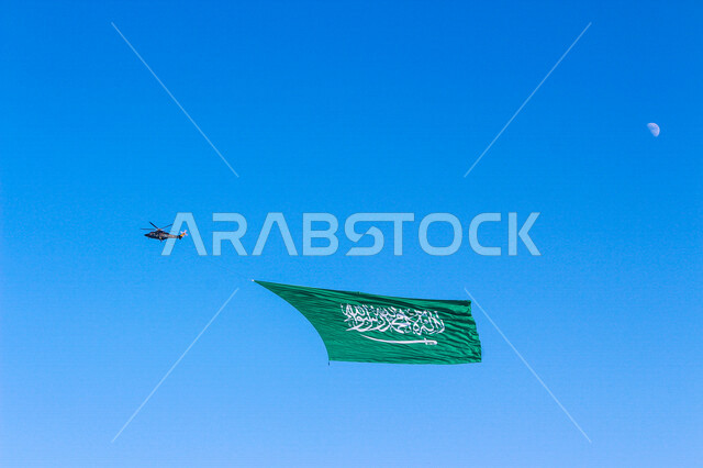 Helicopter with the Saudi flag flying in the sky, Saudi Arabia, Celebrating the national day, the national day of the kingdom, the banner of monotheism and Islam