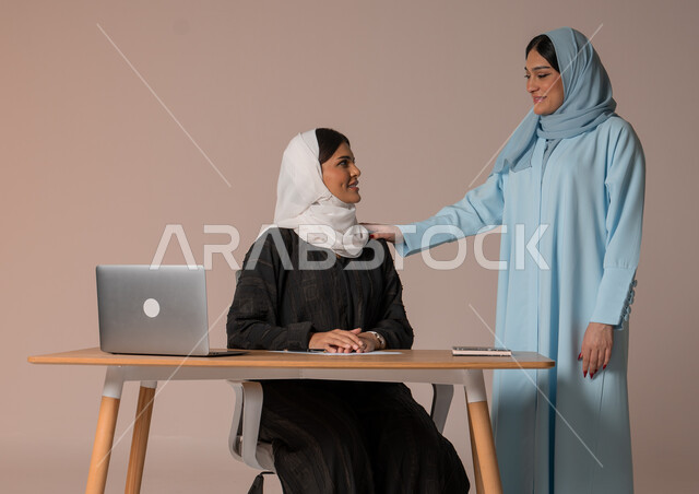 تدريب وتطوير الموظفين وتشجيعهم، الإجتماع في مقر العمل ومناقشة المهام، بورتريه لإمرأتان عربيتان خليجيتان سعوديتان محجبتان داخل مقر الشركة، بيئة عمل مريحة ومتطورة، العمل الجماعي وروح الفريق الواحد، خلفية بيج