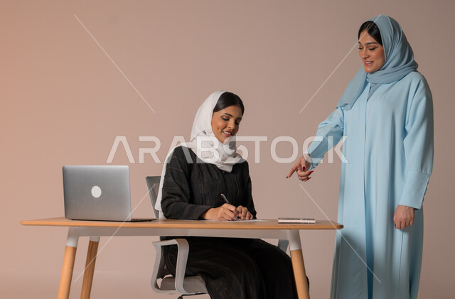 تعليم اساليب العمل والتطوير المهني، متابعة إنجازات مهام الموظفين، إمرأتان عربيتان خليجيتان سعوديتان محجبتان تقومان بتطوير الخطط وحل المشكلات لتحقيق أهداف الشركة، الانتباه للملاحظات وتدوينها، نمط الحياة وبيئة العمل السعودي، خلفية بيج