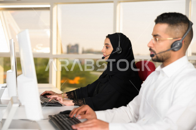 موظفان عربيان خليجيان سعوديان يعملان في خدمة العملاء، موظف وموظفة يرتديان سماعة الاتصال، استعلامات واستفسارات، الاجابه على اسئلة العملاء، اجراء اتصال فيديو من خلال الحاسوب، متابعة وتطوير العمل