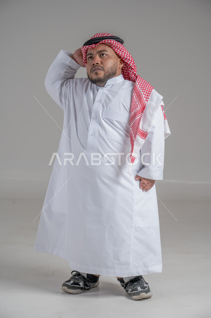 التمكين الاجتماعي لذوي الهمم، بورتريه لشاب عربي خليجي سعودي قصير القامة يرتدي الثوب التقليدي والشماغ يقوم بتحريك يديه بايماءات تدل على السعادة والسرور، صورة الجسم بالطول الكامل، خلفية رمادية