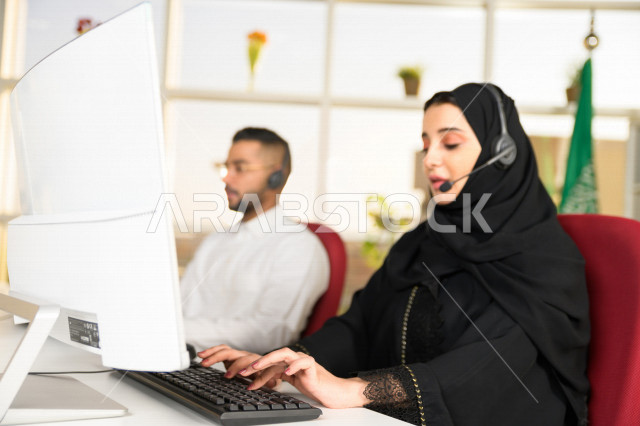 موظفان عربيان خليجيان سعوديان يعملان في خدمة العملاء، موظف وموظفة يرتديان سماعة الاتصال، استعلامات واستفسارات، الاجابه على اسئلة العملاء، اجراء اتصال فيديو من خلال الحاسوب، متابعة وتطوير العمل