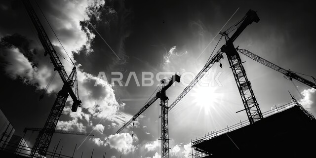 أعمال المقاولات والتطوير العقاري، مفهوم تحسين البنية التحتية للبلاد، صورة بالأبيض والأسود للرافعات العالية ومعدات البناء الضخمة، الأساسات والهياكل الحديدية للمشروعات الحديثة، التطور المعماري والحضاري في المملكة العربية السعودية، تشييد المباني والمشاريع السكنية