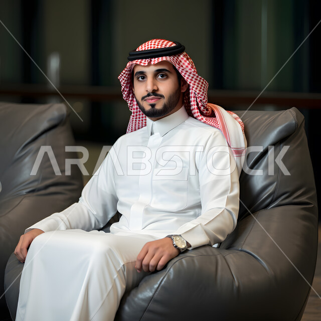 مفهوم الهيبة والرجولة، الأناقة والاهتمام بالمظهر الخارجي، صورة مقربة لرجل عربي خليجي سعودي يرتدي الزي التقليدي والشماغ يجلس على كرسي بين باج، النظر الى الكاميرابتعابير السرور والثقة بالنفس