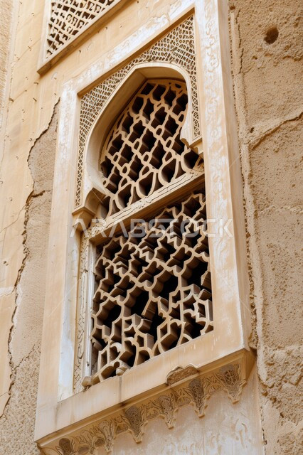 الفنون والتصاميم الهندسية المعمارية على الطراز الاسلامي للنوافذ، نافذة مشربية خشبية منحوتة بأنماط هندسية معقدة، الأناقة والتراث الثقافي التقليدي في منازل المملكة العربية السعودية