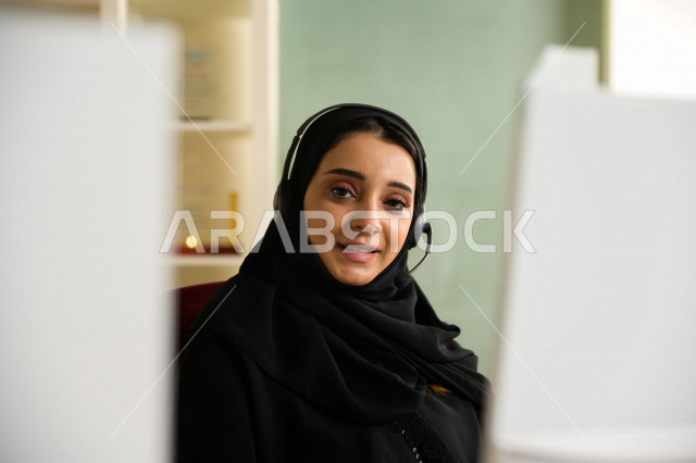 A Saudi Arabian Gulf employee working in customer service and wearing a headset, inquiries and inquiries, answering customer questions, making video calls through a computer, following up and developing work