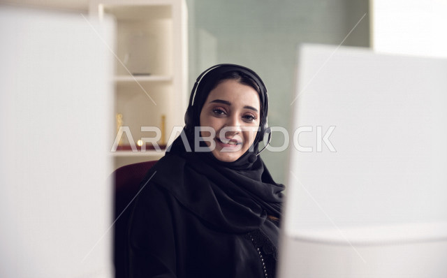 موظفة عربية خليجية سعودية تعمل في خدمة العملاء وترتدي سماعة الاتصال، استعلامات واستفسارات، الاجابه على اسئلة العملاء، اجراء اتصال فيديو من خلال الحاسوب، متابعة وتطوير العمل
