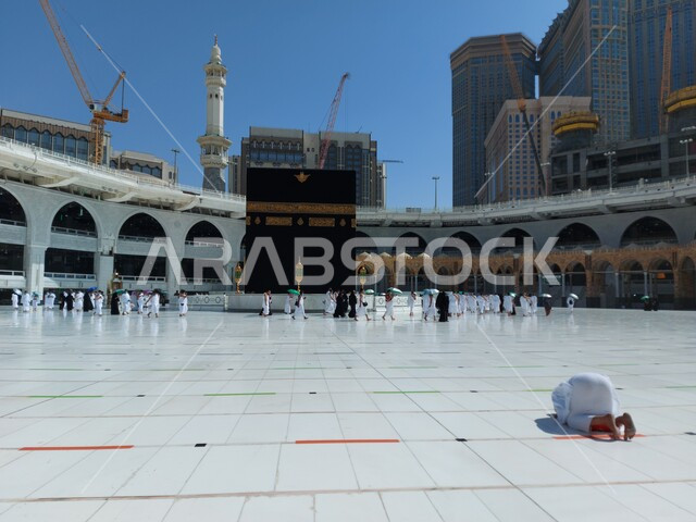 أداء الفرائض الدينية ومناسك الحج والعمرة، الحرم المكي الشريف في أيام انتشار فايروس كورونا في المملكة العربية السعودية ، رجل عربي خليجي سعودي يرتدي لباس الإحرام يؤدي فريضة الصلاة، اتباع اجراءات الوقاية و السلامة من كوفيد ١٩، معالم اسلاميه دينية مشهورة في السعودية