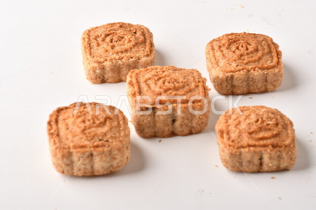 معمول محشو بالتمر ، مربع الشكل من الحلويات الشعبية الهشة اللذيذة على خلفية بيضاء ، صورة لكعك العيد الشهي محشو بالتمر ، حلويات شعبية طازجة