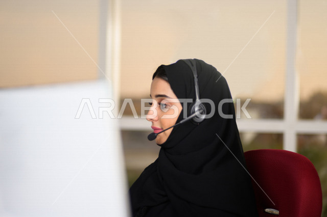 موظفة عربية خليجية سعودية تعمل في خدمة العملاء وترتدي سماعة الاتصال، استعلامات واستفسارات، الاجابه على اسئلة العملاء، اجراء اتصال فيديو من خلال الحاسوب، متابعة وتطوير العمل