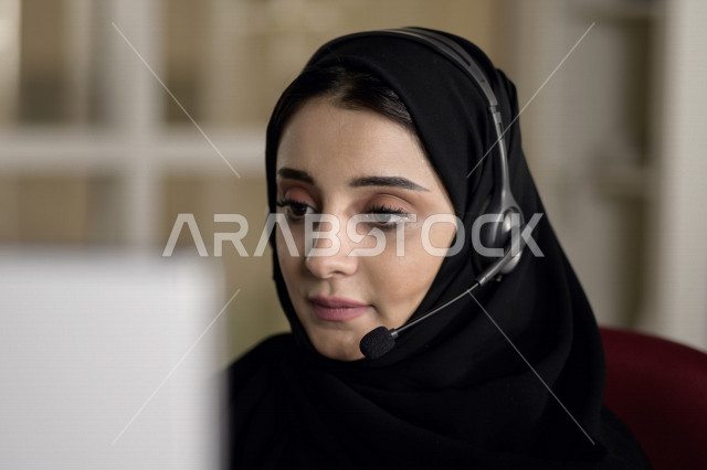 A Saudi Arabian Gulf employee working in customer service and wearing a headset, inquiries and inquiries, answering customer questions, making video calls through a computer, following up and developing work