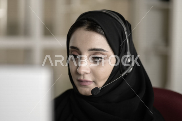 موظفة عربية خليجية سعودية تعمل في خدمة العملاء وترتدي سماعة الاتصال، استعلامات واستفسارات، الاجابه على اسئلة العملاء، اجراء اتصال فيديو من خلال الحاسوب، متابعة وتطوير العمل