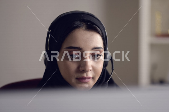 موظفة عربية خليجية سعودية تعمل في خدمة العملاء وترتدي سماعة الاتصال، استعلامات واستفسارات، الاجابه على اسئلة العملاء، اجراء اتصال فيديو من خلال الحاسوب، متابعة وتطوير العمل