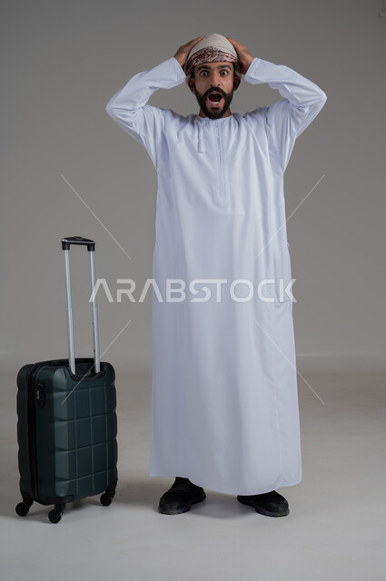 التأخر على موعد الانطلاق على موعد الانطلاق، مفهوم السياحة في إجازة الصيف، القيام بالجولات الترفيهية، بورتريه لشاب عربي عماني يرتدي الدشداشة والعمامة يضع يده على رأسه بتعابير الدهشة وبجانبه حقيبة الامتعة، الجسم بالطول الكامل, خلفية بيضاء