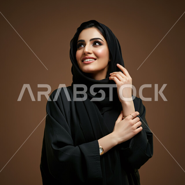 الاعتناء بالمظهر الخارجي والشياكة والأناقة, تعابير السعادة والسرور ، بورتريه مقرب لإمرأة عربية خليجية سعودية محجبة مبتسمة ترتدي العباءة السوداء تنظر إلى مكان ما في الأعلى بإيماءات الثقة بالنفس والفرح، مفهوم الأنوثة والنعومة لدى النساء السعوديات، خلفية بنية