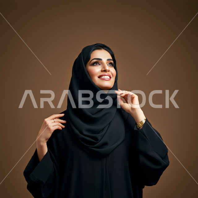الاعتناء بالمظهر الخارجي والشياكة والأناقة, تعابير السعادة والسرور ، بورتريه مقرب لإمرأة عربية خليجية سعودية محجبة مبتسمة ترتدي العباءة السوداء تنظر إلى مكان ما في الأعلى بإيماءات الثقة بالنفس والفرح، مفهوم الأنوثة والنعومة لدى النساء السعوديات، خلفية بنية