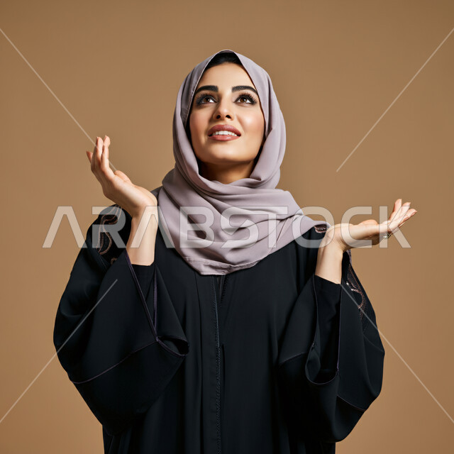 النظر والتأمل بإيماءات السعادة والسرور، مفهوم النعومة والأنوثة، الاناقة والاهتمام بالمظهر الخارجي، بورتريه مقرب لإمرأة عربية خليجية سعودية محجبة مبتسمة ترتدي العباءة السوداء تنظر إلى الأعلى بتعابير الإنبهار والإعجاب بشيء ما، خلفية بنية