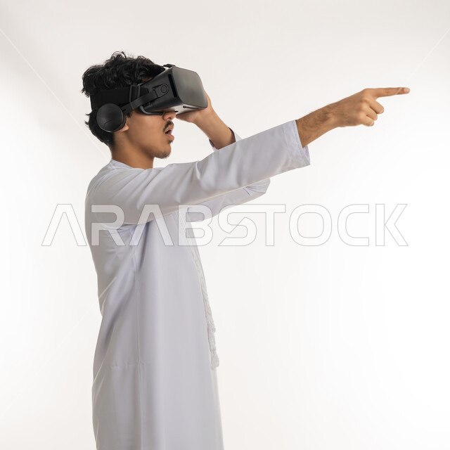 Modern technological devices and technologies, distant future vision, portrait of a young Arab Gulf Emirati man wearing Kandora and 3D virtual reality glasses pointing index finger to a distant place, imaginary world simulation, white background