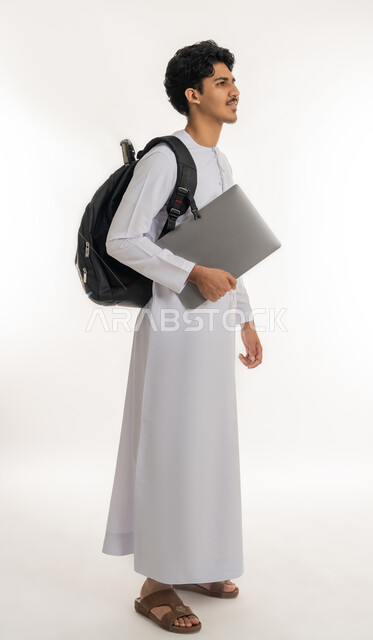 الجد والاجتهاد للوصول إلى النجاح والتفوق، أهمية التعليم في بناء المستقبل, تطوير المناهج التعليمية في الإمارات، متابعة الدروس والواجبات، بورتريه لشاب عربي خليجي إماراتي يرتدي الكندورة يحمل حقيبة الظهر والكتب المدرسية، الطول الكامل للجسم, خلفية بيضاء