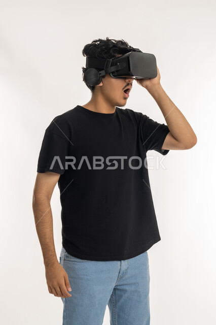 المتعة و التسلية بالمشاهدة عبر نظارة الواقع الافتراضي، بورتريه لشاب عربي خليجي إماراتي يرتدي الزي الكاجوال ينظر من خلال نظارات ثلاثية الأبعاد (الفي ار), الاندماج ومحاكاة العالم الخيالي والنظر الى الافلام الواقعيه، التطور التقني والتكنولوجي, خلفيه بيضاء