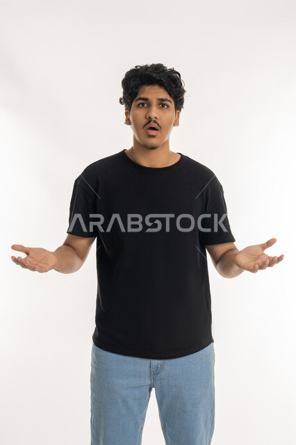 الإستفهام حول موضوع معين, بورتريه لشاب عربي خليجي إماراتي يرتدي الزي الكاجوال ينظر الى الكاميرا ويرفع يديه نحو الأعلى بإيماءات عدم المعرفة, الشعور بالحيرة ، الغموض وعدم الوضوح، الإستغراب والاستفسار عن أمر ما، خلفية بيضاء