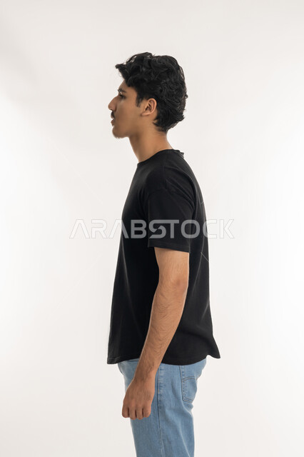 النظر الى شيء ما بإيماءات الجدية، بورتريه من الجانب لشاب عربي خليجي إماراتي يرتدي الزي الكاجوال يركز في مكان محدد, الاهتمام بالأناقة والمظهر الخارجي، الوقوف باستقامة وثبات، مفهوم الرجولة العربية, خلفية بيضاء