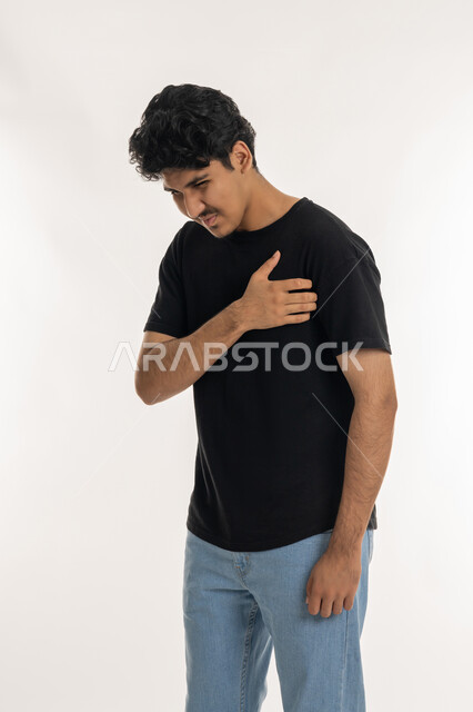 زيادة في معدل ضربات القلب، الاحساس بذبحه صدريه، بورتريه لشاب عربي خليجي إماراتي يرتدي الزي الكاجوال يضع يده على صدره، الشعور بحالة سيئة من الوخز والألم, اضطرابات وأمراض قلبية, الإرهاق والضغوطات النفسية, ضرورة الذهاب للطبيب لتلقي العلاج المناسب، خلفية بيضاء