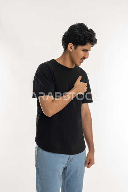 ضرورة الذهاب للطبيب لتلقي العلاج المناسب، الاحساس بذبحه صدريه، بورتريه لشاب عربي خليجي إماراتي يرتدي الزي الكاجوال يضع يده على صدره، الشعور بحالة سيئة من الوخز والألم, اضطرابات وأمراض قلبية, التعب والإرهاق والضغوطات النفسية, خلفية بيضاء