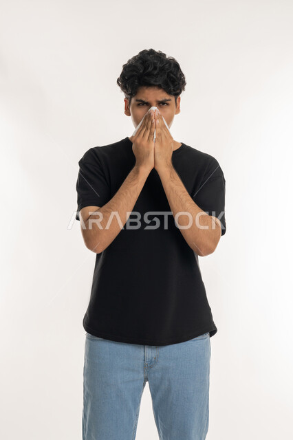 الحاجة إلى العلاج والدواء, التهاب الأنف و الجيوب التحسسية, الشعور بالمرض و الزكام, بورتريه لشاب مراهق عربي خليجي إماراتي يرتدي الزي الكاجوال يضع منديل ورقي على وجهه بإيماءات العطاس, خلفية بيضاء