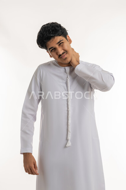 آلام العنق والعمود الفقري, الحاجة للعلاج الفيزيائي، الإحساس بالتعب والإرهاق, وجع مفاصل و عظام الرقبة, بورتريه لشاب مراهق عربي خليجي إماراتي يرتدي الكندورة يضع يده حول عنقه بإيماءات الألم, خلفية بيضاء