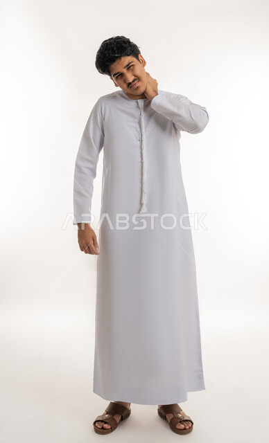 وجع مفاصل و عظام الرقبة, آلام العنق والعمود الفقري, الحاجة للعلاج الفيزيائي، الإحساس بالتعب والإرهاق, بورتريه لشاب مراهق عربي خليجي إماراتي يرتدي الكندورة يضع يده حول عنقه بإيماءات الألم, الجسم بالطول الكامل, خلفية بيضاء