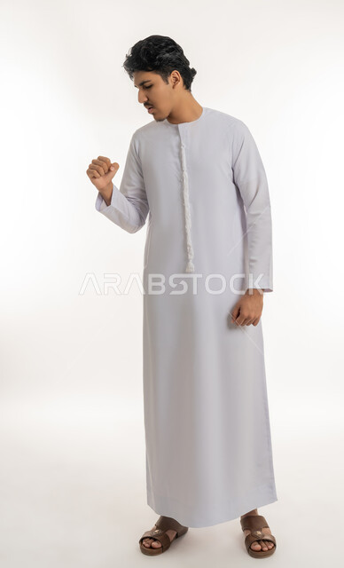 الانفلونزا والتهاب الرئة, الشعور بالمرض و الكحة, الحاجة إلى زيارة الطبيب و العلاج, الإصابة بفايروس كورونا, بورتريه لشاب مراهق عربي خليجي إماراتي يرتدي الكندورة يرفع يده إلى فمه بإيماءات السعال, الجسم بالطول الكامل, خلفية بيضاء