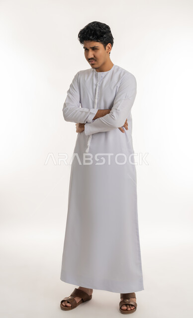 الإحساس بآلام في المعدة, طلب المساعدة للذهاب إلى الطبيب، الحاجة للدواء ووضع خطة علاجية, عسر الهضم والشعور بالمغص، بورتريه لشاب مراهق عربي خليجي إماراتي يرتدي الكندورة يضع يديه على بطنه بإيماءات الألم, الجسم بالطول الكامل, خلفية بيضاء