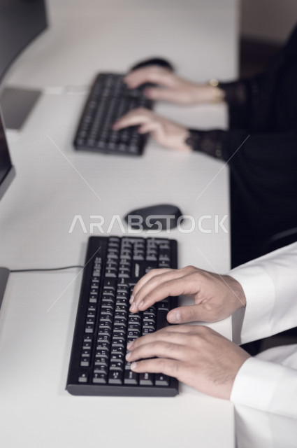 Close-up of the hand of a Saudi Arabian Gulf man working in customer service, inquiries and inquiries, answering customer questions, making video call through the computer, follow-up and development of work, data entry