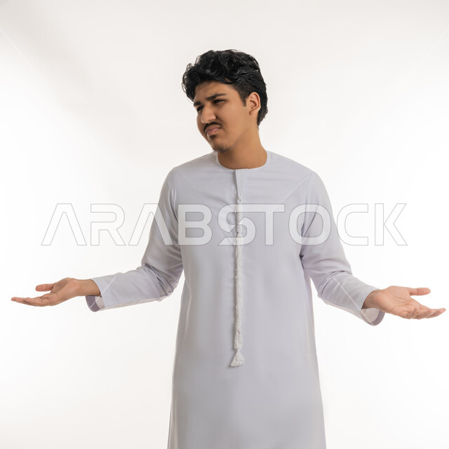 تعابير عدم الفهم و الحيرة و الاستفهام, الاستفسار و التساؤل عن شيء معين, بورتريه لشاب مراهق عربي خليجي إماراتي يرتدي الكندورة يشير بيديه بإيماءات الاستغراب و التعجب, خلفية بيضاء