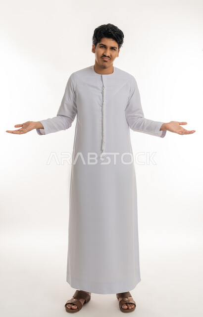 تعابير الاستفهام و عدم الفهم و الحيرة, الاستفسار و التساؤل عن شيء معين, بورتريه لشاب مراهق عربي خليجي إماراتي يرتدي الكندورة يشير بيديه بإيماءات الاستغراب و التعجب, الجسم بالطول الكامل, خلفية بيضاء