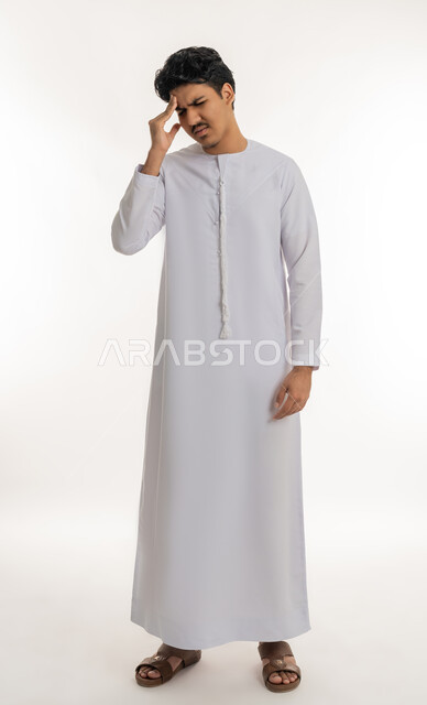 الإحساس بالدوار و وجع الرأس, الحاجة إلى العلاج و الراحة, الشعور بالمرض و  التعب, آلام الشقيقة والصداع النصفي, بورتريه لشاب مراهق عربي خليجي إماراتي يرتدي الكندورة يضع يده على رأسه بإيماءات الانزعاج و الألم, الجسم بالطول الكامل, خلفية بيضاء