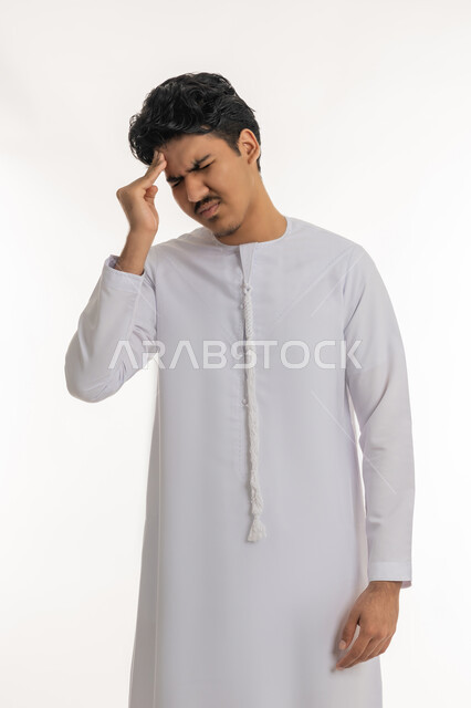 آلام الشقيقة والصداع النصفي, الإحساس بالدوار و وجع الرأس, الحاجة إلى العلاج و الراحة, الشعور بالمرض و  التعب, بورتريه لشاب مراهق عربي خليجي إماراتي يرتدي الكندورة يضع يده على رأسه بإيماءات الانزعاج و الألم, خلفية بيضاء