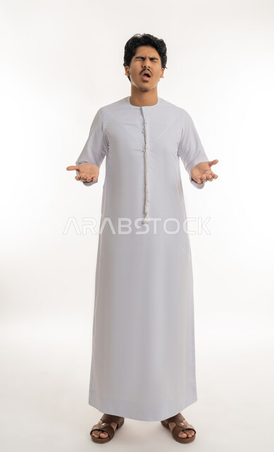 الاستفسار و التساؤل عن شيء معين, تعابير الاستفهام و عدم الفهم و الحيرة, بورتريه لشاب مراهق عربي خليجي إماراتي يرتدي الكندورة يشير بيديه بإيماءات الاستغراب و التعجب, الجسم بالطول الكامل, خلفية بيضاء