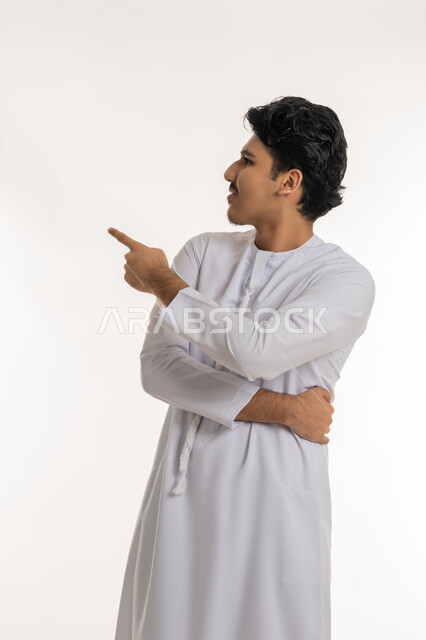 الإشارة و التوضيح إلى شيء ما, تحديد موقع معين, الدلالة على مكان عنصر، بورتريه لشاب مراهق عربي خليجي إماراتي يرتدي الكندورة ينظر إلى الأعلى و يشير بإصبع السبابة إلى شيء ما، خلفية بيضاء