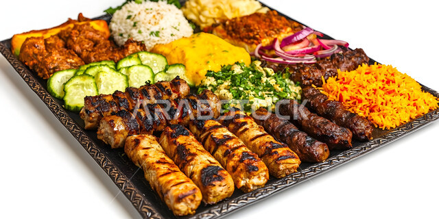 وجبة ذات قيمة غذائية عالية, وصفات المطبخ السعودي الغني بالنكهات المميزة، أطعمة غنية بالبروتين، مطاعم للمأكولات العربية الشرقية، طبق معدني مكون من أسياخ اللحم والصلصات والخضروات، خلفية بيضاء