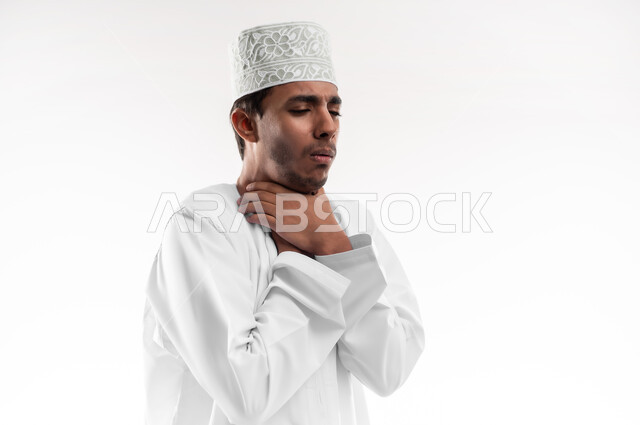 Feeling sick and coughing, flu and pneumonia, need for treatment and medication, close-up portrait of a young Gulf Arab Omani man wearing a dishdasha and a sleeve, putting his hands on his neck with gestures of shortness of breath, feeling suffocated and extremely tired, white background