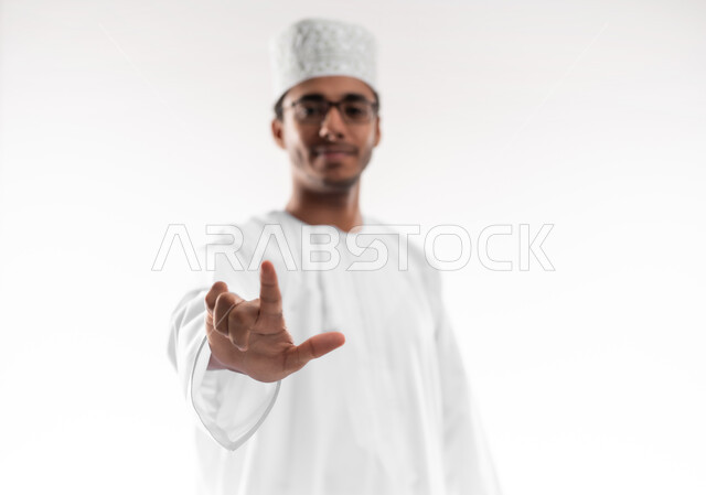 تعليم لغات الإشارة للصم والبكم، الاهتمام بالأناقة والمظهر الخارجي، بورتريه مقرب لشاب عربي خليجي عماني يرتدي الدشداشة والكمه والنظارة الطبية يرفع إصبعين بدلالة الرقم اثنان، التواصل مع ذوي الهمم سمعياً أو صوتياً، خلفية بيضاء