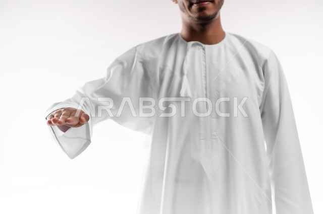 قياس حجم الأشياء، مفهوم تقديم وعرض عنصر معين، بورتريه مقرب لشاب عربي خليجي عماني يرتدي الدشداشة يرفع يده للاعلى بإيماءات تحديد طول شيء ما، خلفية بيضاء