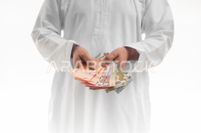 النهضة الاقتصادية في سلطنة عمان، عرض الإصدار الجديد للنقود الورقية العمانية، العملة الرسمية المتداولة في أسواق البلاد، بورتريه مقرب ليدي رجل شايب عربي خليجي عماني يرتدي الدشداشة التقليدية يقف ويمسك أوراق النقدية من عدة فئات، خلفية بيضاء