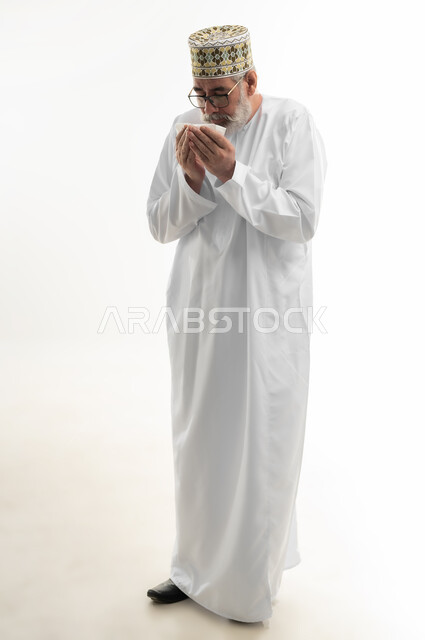 ضرورة أخذ العلاج المناسب، الإرهاق والتعب والحاجة للراحة، العطاس والكحه وأعراض الرشح، الإصابة بالزكام والانفلونزا، بورتريه لرجل شايب عربي خليجي عماني يرتدي الدشداشة والكمه العمانية يمسك المنديل الورقي بيده لمنع انتشار العدوى، الجسم بالطول الكامل، خلفية بيضاء